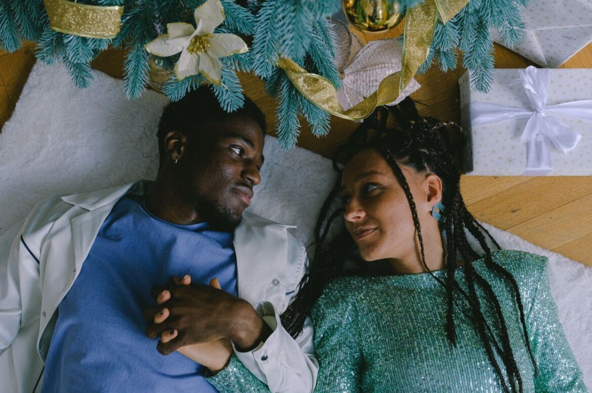 Couple are lying on the floor under a Christmas tree